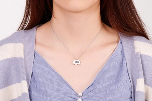 Silver stainless steel elephant pendant necklace worn by a model on a purple outfit