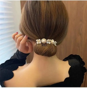 Detalle de pinza floral para el cabello con perlas y flores blancas en moño elegante
