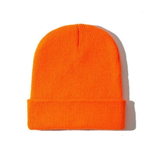 Detailed texture of vibrant orange knitted beanie showing high-quality wool fabric