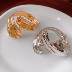 Detail of twisted textured open bangles in polished gold and silver metallic finish
