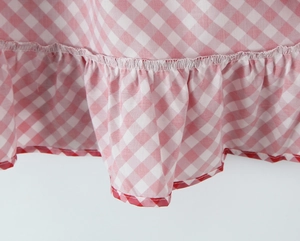 Gros plan d'une robe en coton à carreaux roses avec ourlet à volants et liseré rouge
