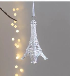 Detailed view of a clear acrylic Eiffel Tower ornament with a white ribbon and silver ring
