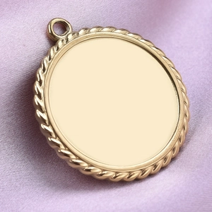 Golden stainless steel round pendant with twisted rope edge on purple fabric background