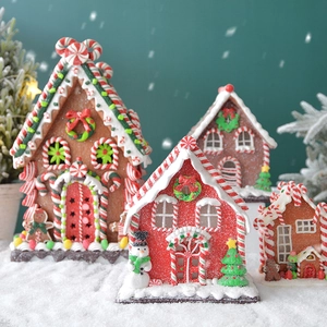 Close-up of lighted clay gingerbread houses with icing roofs on faux snow setting
