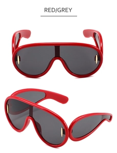 Close-up of red oversized shield sunglasses with dark grey lenses and gold accents