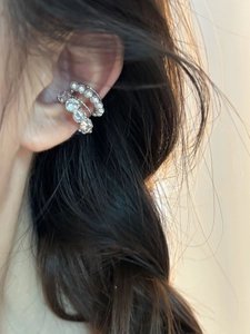 Détail de bagues d'oreille multicouches avec perles et zircons portées avec élégance