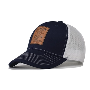 Detail of the deep blue trucker hat with a leather patch featuring a reindeer and wild nature text