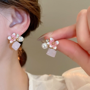 Close-up of pink cherry blossom earrings with pearls and crystals on a model