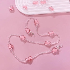 Pink resin heart bead chain detail with white silicone loops on wavy white tray