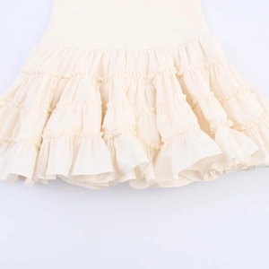 Détail de l'ourlet à plusieurs niveaux de cette robe blanc crème avec des volants