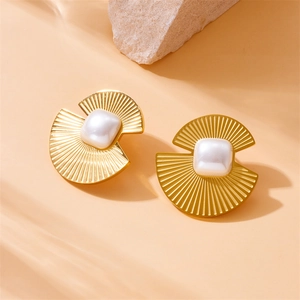 Golden fan-shaped earrings with square pearl inlays on a natural stone background