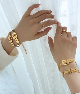 Detail of 18K gold plated belt buckle triple layer chain bracelet worn by a model