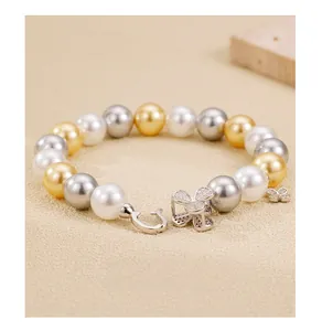 Detail of 925 sterling silver clover clasp and tricolor pearl bracelet with butterfly charm