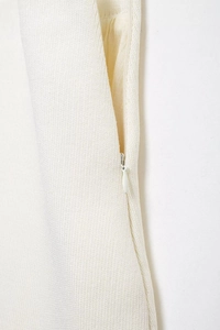 Detail shot of invisible zipper stitching on creamy white knitted elegant skirt