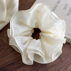 Macro detail of creamy white four-layer oversized scrunchie with subtle plaid texture