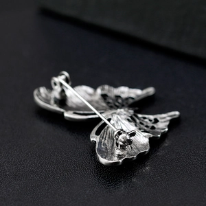 Antique silver butterfly brooch with detailed shell inlay and secure pin clasp on leather