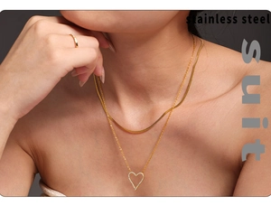Detail of gold snake chain and heart pendant necklace set on model in stainless steel