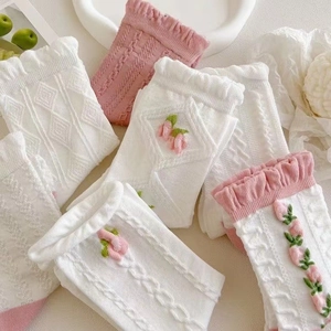 Detail von cremeweißen Baumwollsocken mit Spitzenrand und besticktem Tulpenmuster