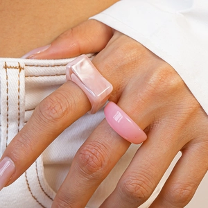 Detail of pink marble resin square ring and translucent round ring set worn by model