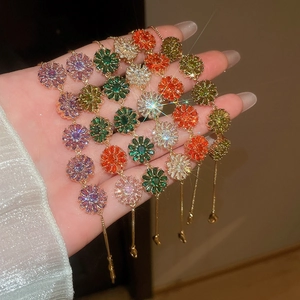 Close-up of stacked 18k gold plated bracelets with colorful zircon flower pendants