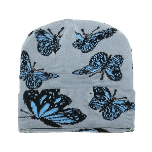 Texture détaillée du bonnet en maille gris clair avec motifs papillons bleus et noirs