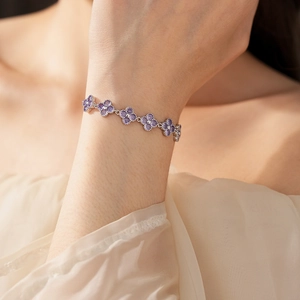 Close-up of silver floral bracelet with purple zircon stones on a model's wrist