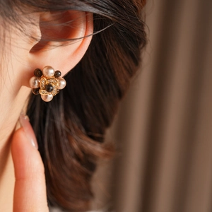 Gros plan de boucles d'oreilles fleurs en perles plaquées or portées par un mannequin