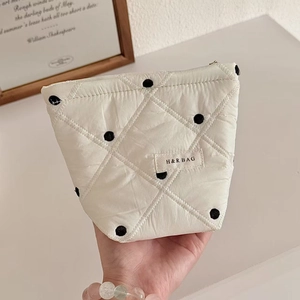 Détail de la trousse à maquillage matelassée à pois en nylon blanc avec étiquette H&R BAG