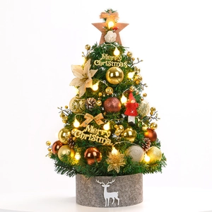 Miniature green Christmas tree with gold ornaments, pine cones, and LED lights in a grey pot