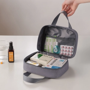 Portable gray travel first aid bag with handle and mesh pockets for medicine storage