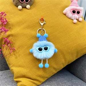 Detailed view of blue plush keychain with knit hat and sunglasses on yellow background