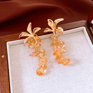 Vue détaillée des boucles d'oreilles fleur dorées avec glands en verre ambre
