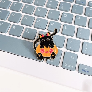 Detail of Halloween black cat enamel pin in pumpkin suit on a laptop keyboard