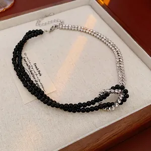 Double-layered beaded necklace with rhinestones and central knot design in a jewelry tray