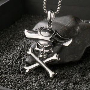Detailed macro shot of vintage silver stainless steel pirate skull pendant on dark stones