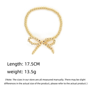 Detail view of 17.5cm gold-plated beaded bracelet with a minimalist bow charm on white background
