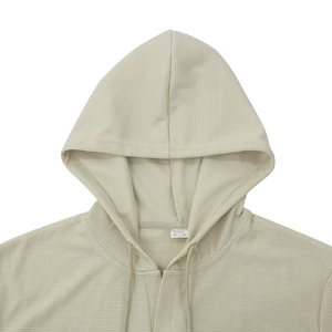 Detail shot of beige waffle knit texture and hoodie drawstring on a men's t-shirt