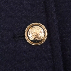 Detailed macro view of a vintage gold embossed button on navy blue tweed fabric jacket