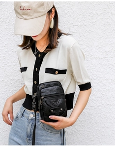 Detail view of black soft PU leather crossbody bag with multiple zippers worn by a model