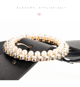 Detail of elegant gold round buckle with faux pearls and rhinestones on black leather belt