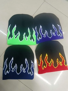 Close-up of four knitted beanies with colorful flame patterns in green, purple, blue, and red