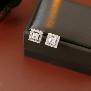 Macro shot of silver square stud earrings with central zircon and pavé setting halo