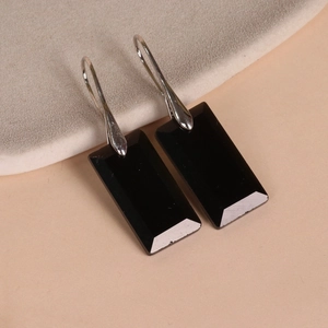 Macro shot of rectangular black faceted stones on silver metal drop earrings for women