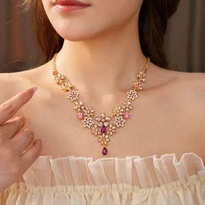 Close-up of vintage floral necklace with pink and purple crystals on a golden chain