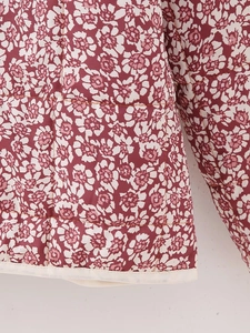 Close-up of floral quilted jacket with square stitching and white piped hem details