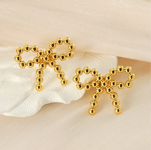 Detail view of 18K gold bow-shaped stud earrings crafted with polished metallic beads