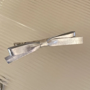 Dettaglio di fermaglio per capelli a fiocco argento con finitura in pelle metallizzata