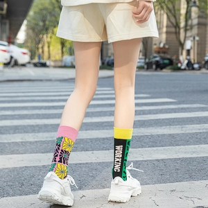 Detail showing asymmetric crew socks with daisy print and WORKING text on white sneakers