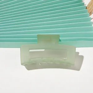 Detail view of light green matte hair claw clip with minimalist geometric hollow design