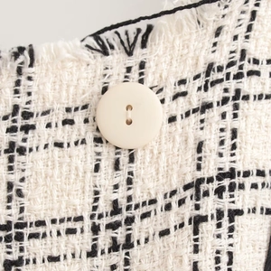 Elegant black and white tweed two-piece set featuring classic woven fabric and button detail